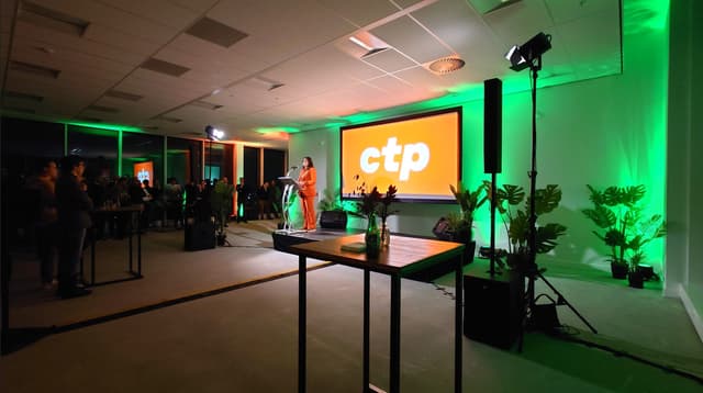 Speaker at a lectern on a stage with a large projection screen