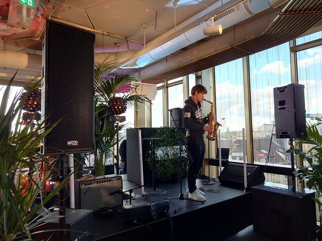 Saxophonist among loudspeakers and audio equipment on a stage