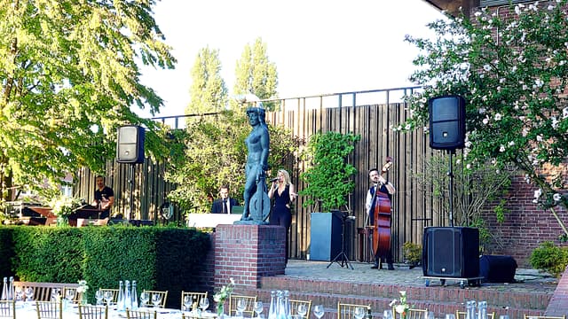 Liveband met zangeres, pianist, contrabassist en geluidstechniek in een tuin