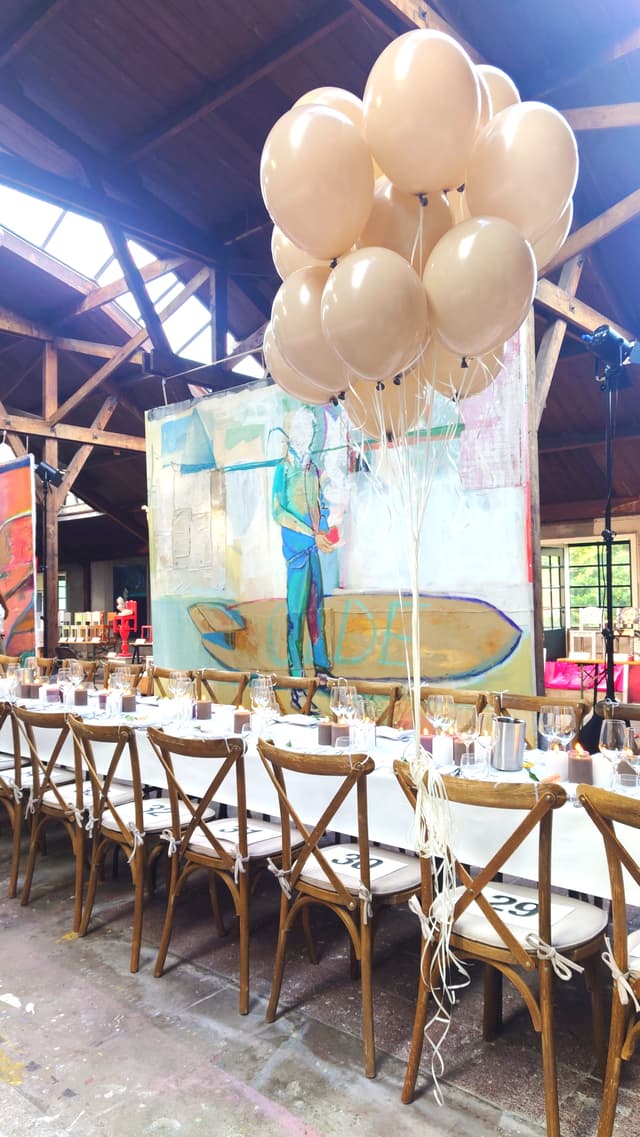 Cream-coloured balloons above a set dining table in an atelier