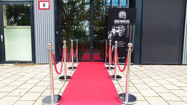Rode loper met chrome afzetpaaltjes en rode koorden bij een entree