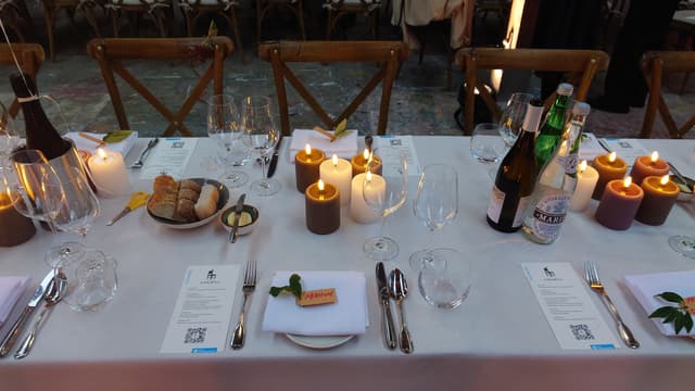 Sfeervol gedekte dinertafel met kaarslicht, glaswerk en menukaarten