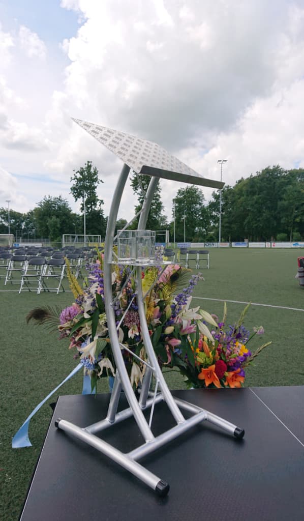 Katheder op een buitenpodium met bloemen en stoelen voor het publiek