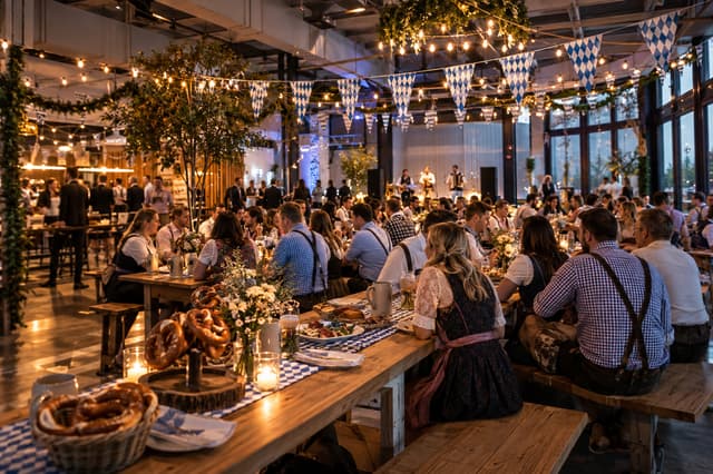 Festive Oktoberfest setting with wooden tables, blue and white flags and warm lighting