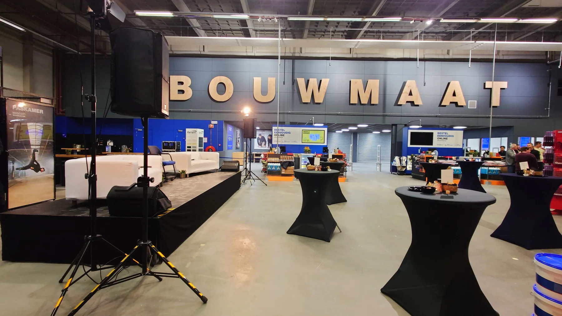Stage with white sofas, speakers and standing tables