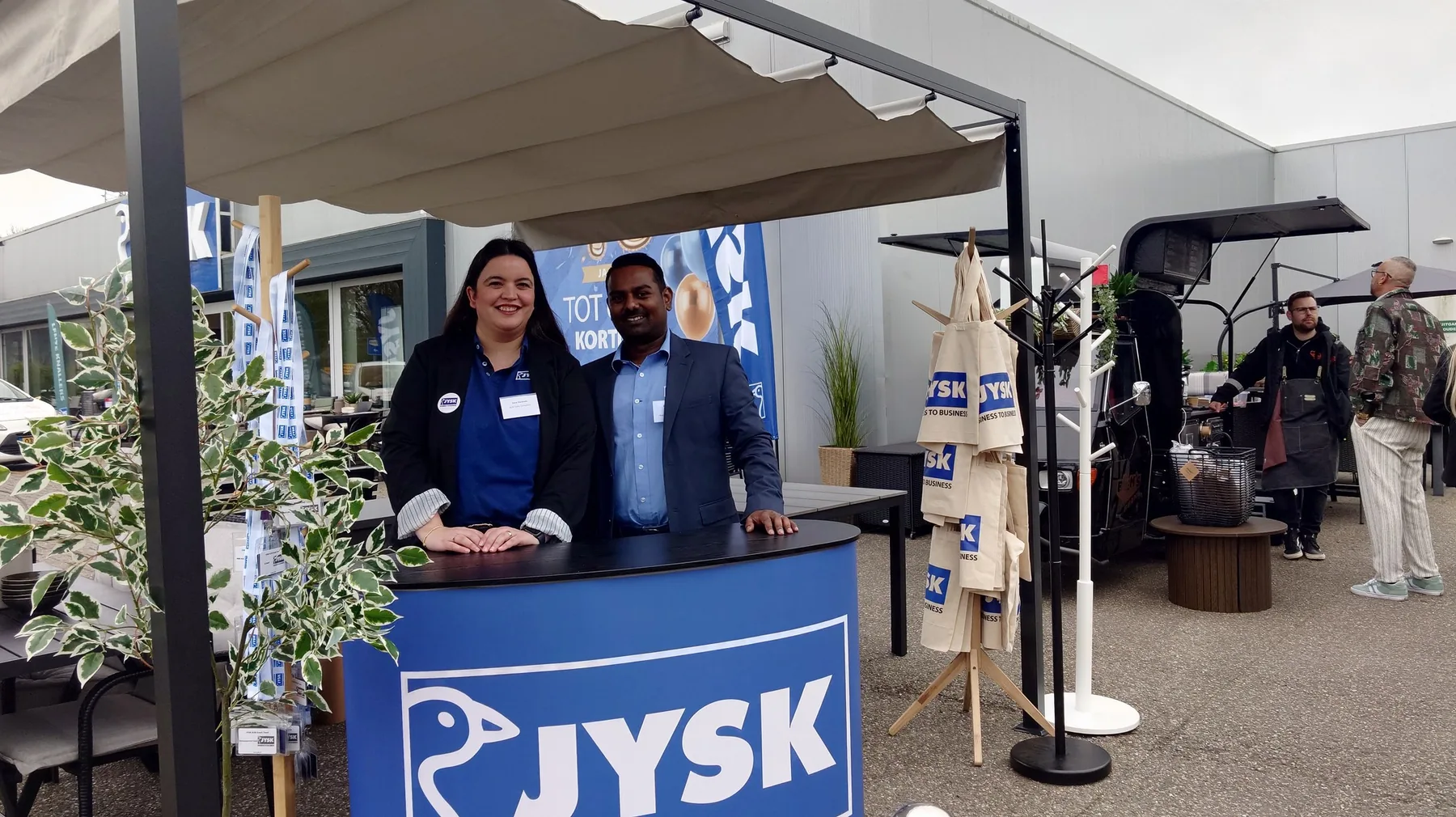 Two hosts at the welcome desk next to the coffee cart