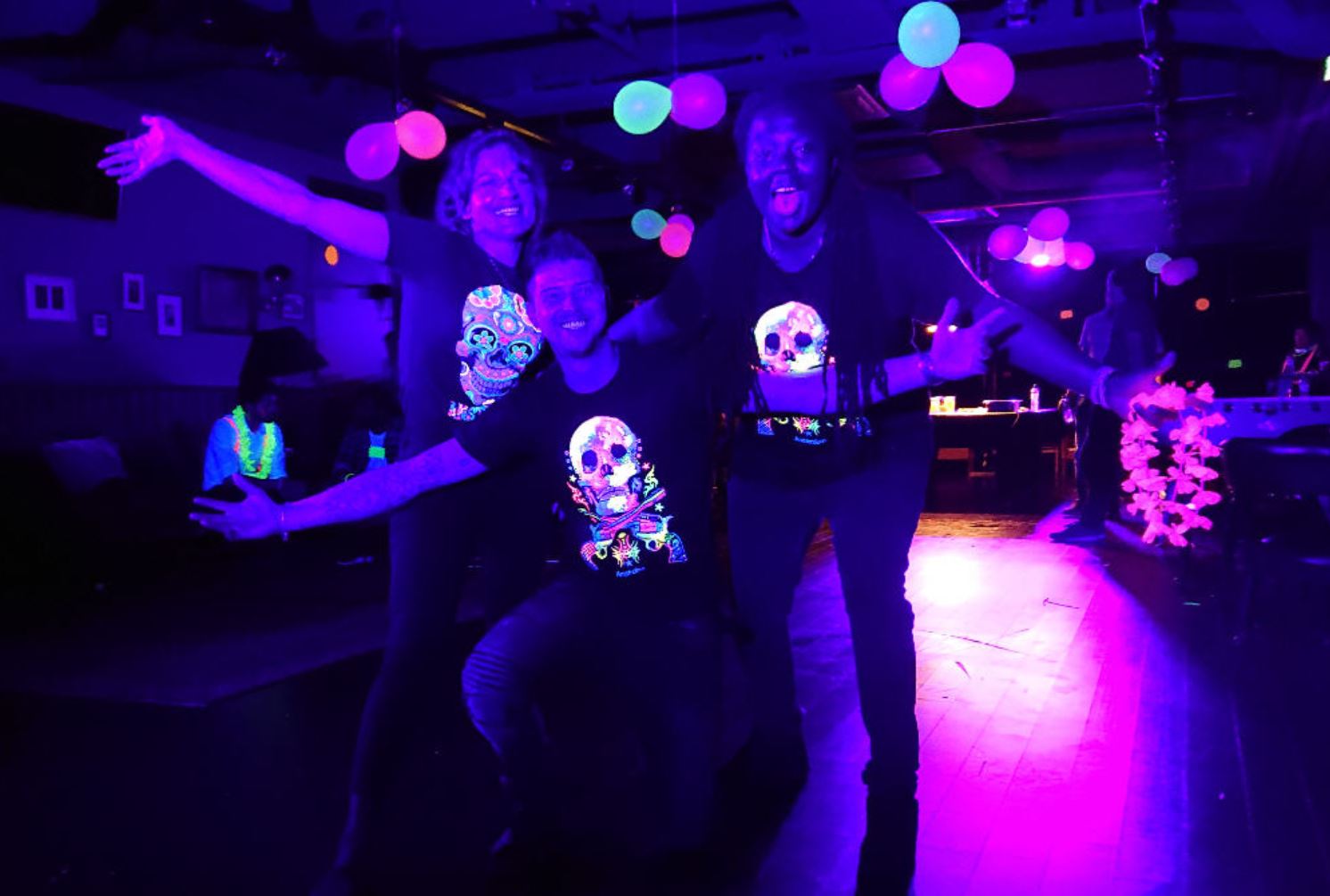 Party guests wearing fluorescent clothing under blacklight