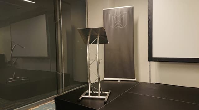Truss lectern on a stage beside a presentation screen